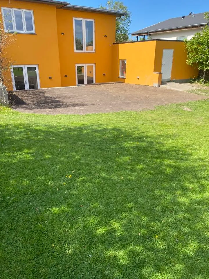 Færdig græsplæne foran gult hus efter anlæg